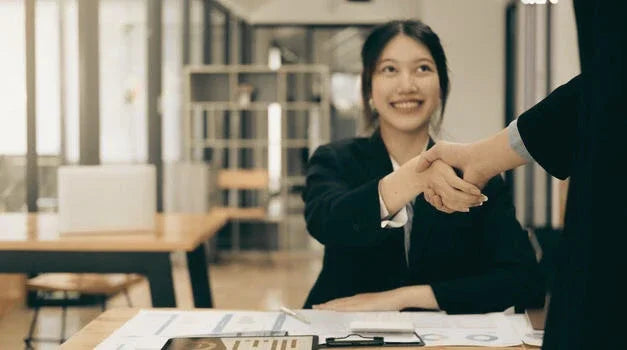 Smiling businesswoman in office shaking hands after a successful negotiation meeting