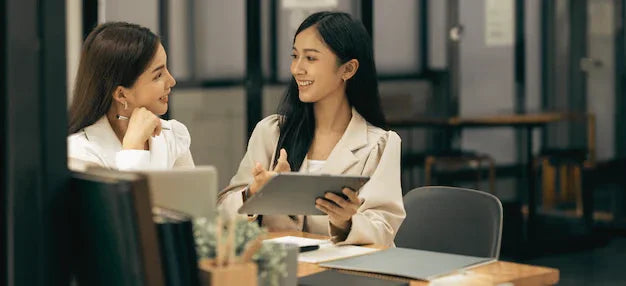 Two professional women discussing business English training at a modern office desk