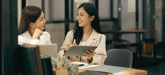 Two professional women discussing business English training at a modern office desk
