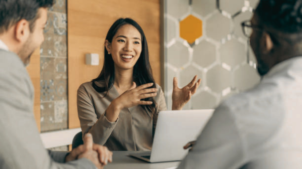 Woman confidently presenting an idea to two colleagues in an office setting