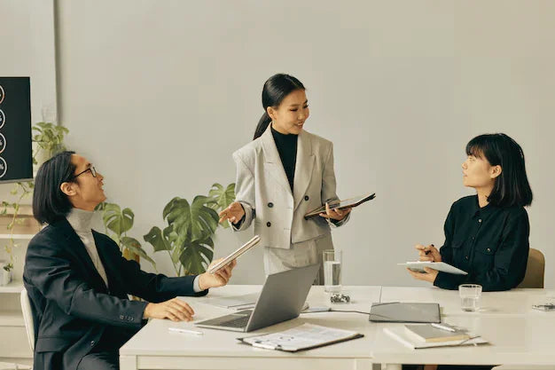Business meeting with three professionals discussing documents around a conference table.